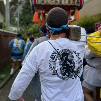 ロゴ入り鯉口シャツで神輿を担ぐ様子